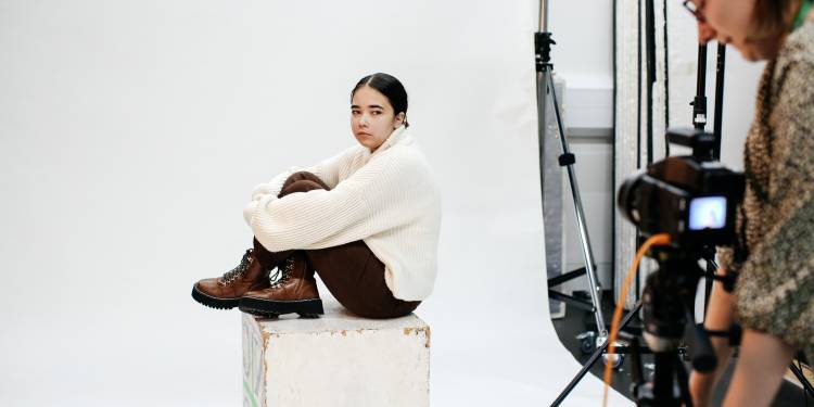 Photographer takes picture of woman sat on white box