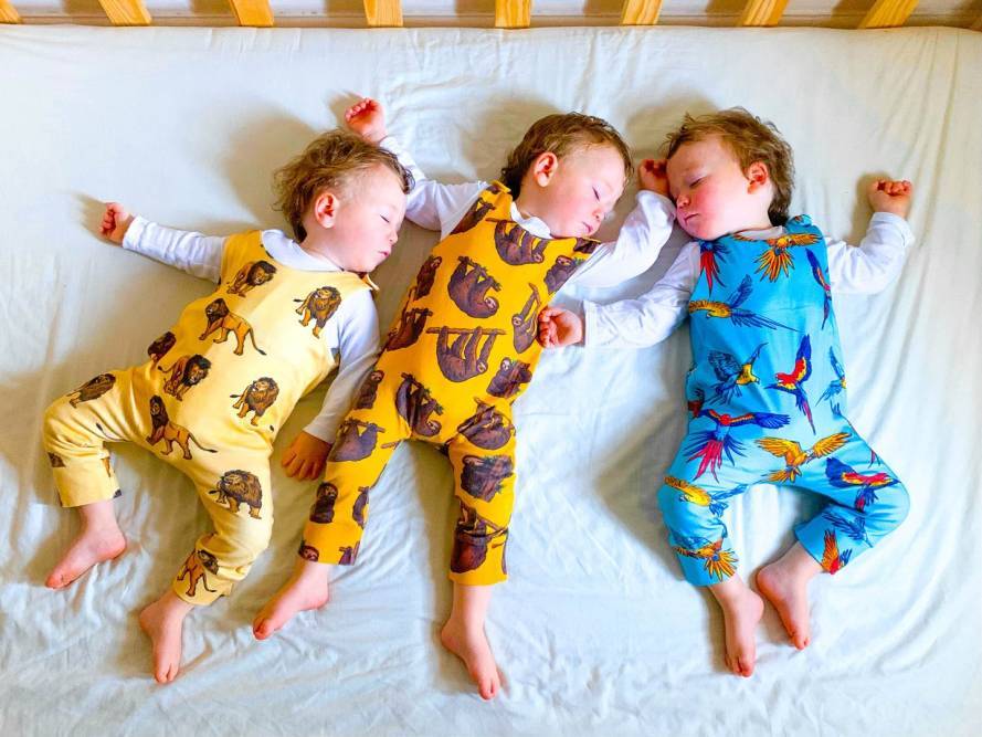 Three babies take a nap wearing Project Panda rompers