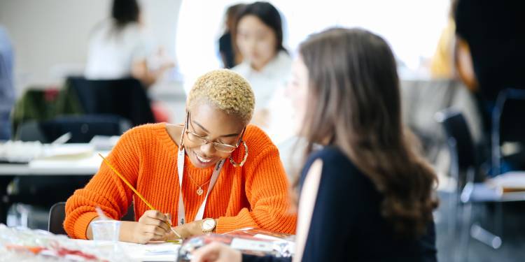 Student works at her desk surrounded by other students