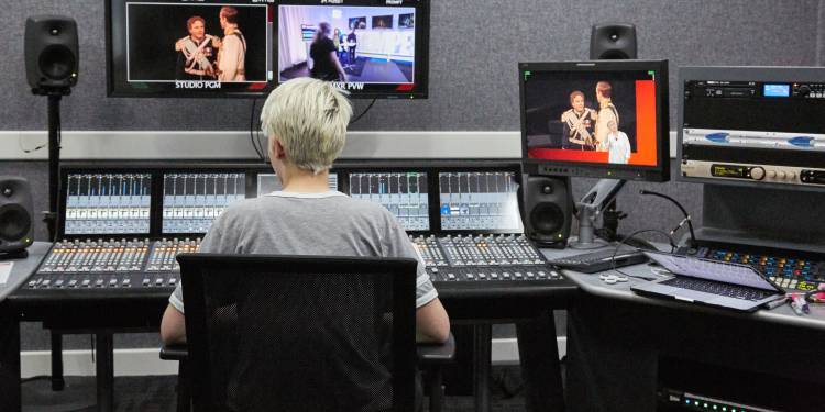 Student sits looking at screen in production room