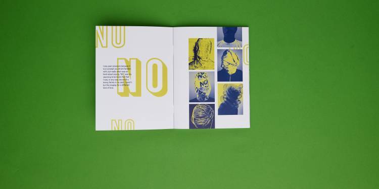 A small book with layered typography and images in shades of blue and yellow laid flat on a green background