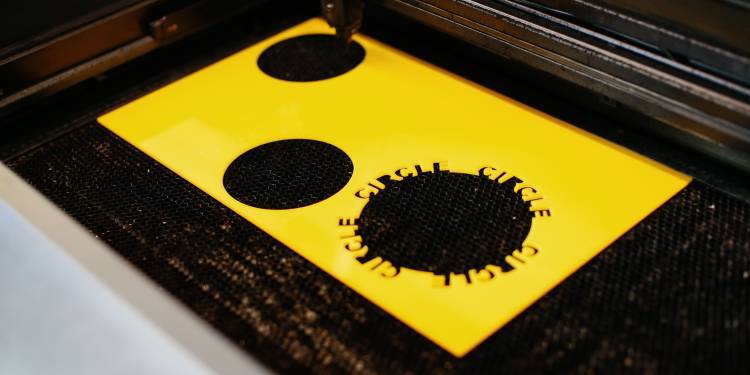 a yellow piece of plastic with circles cut out using the lazer cutter,