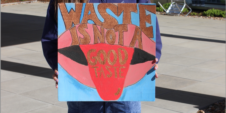 a large pink and red mouth is painted on a blue background with the phrase "waste is not good taste" written in gold on top