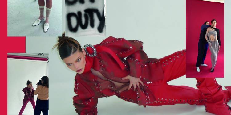 Model in all red boiler suit poses kneeling on forearm 