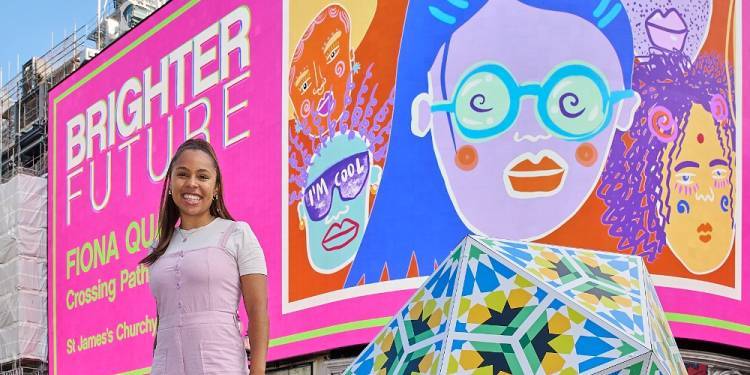 Fiona stands in front of colourful pink billboard featuring her illustrations