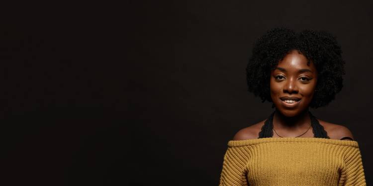 Young student wearing a mustard coloured top smiles to the camera