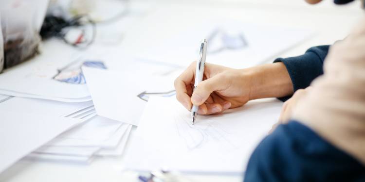 Man drawing with pen on white paper using pen