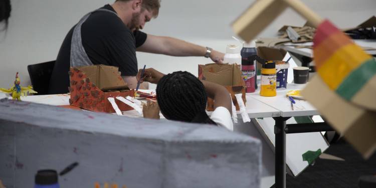 2 people pictured painting cardboard structures