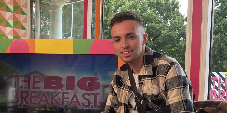 Man sat in chair smiling with TV screen in the background reading 'The Big Breakfast'