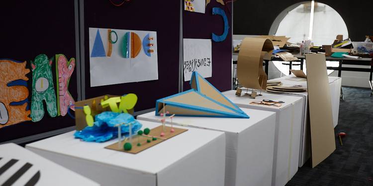 white cardboard boxes with small cardboard sculptures displayed on top
