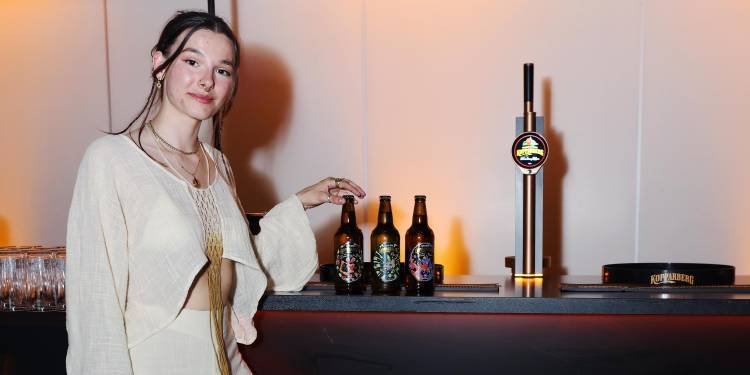 Paulina stands next to three Kopparberg bottles featuring her designs
