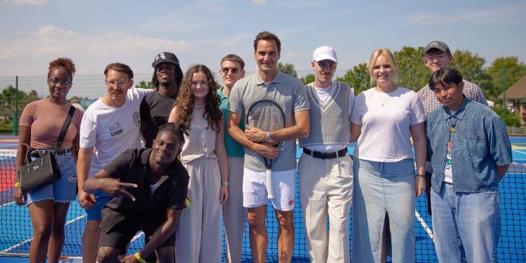 Federer stands on a tennis court alongside Ravensbourne students