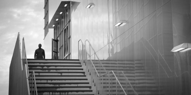 Person walks next to an ominous metal-clad building