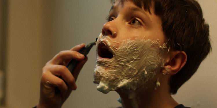Boy shaving with shaving foam on his face