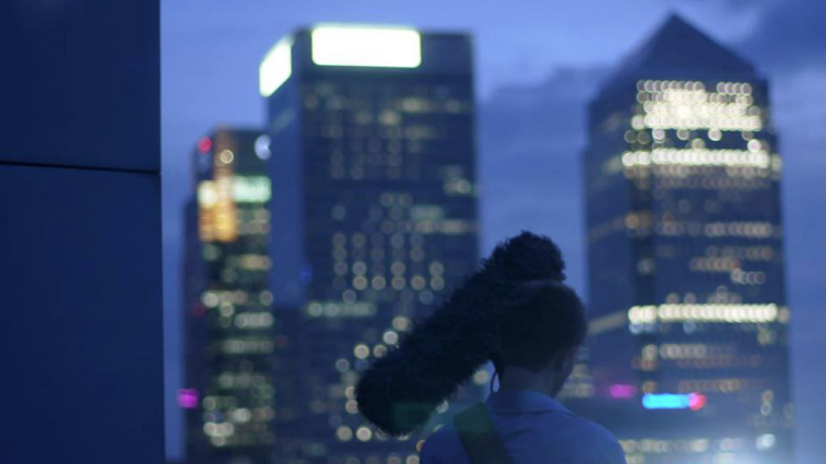 man-with-camera-outside-at-night-with-view-of-london-skyline