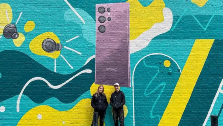 Two females stand in front of mural wall