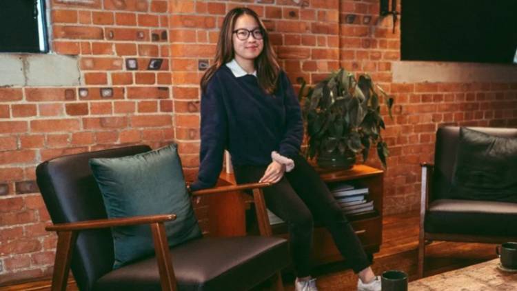 Emily Chow leans against table in her office