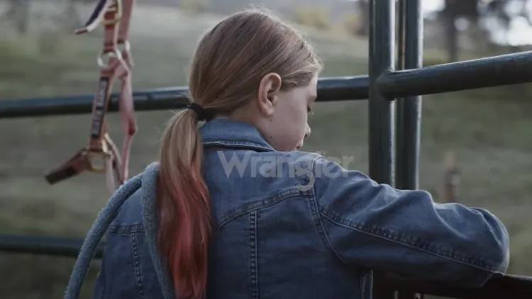 close up of a young girl opens a gate in a field