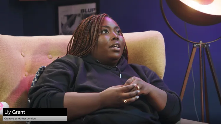 A young black woman with long brown braids sits in a yellow armchair