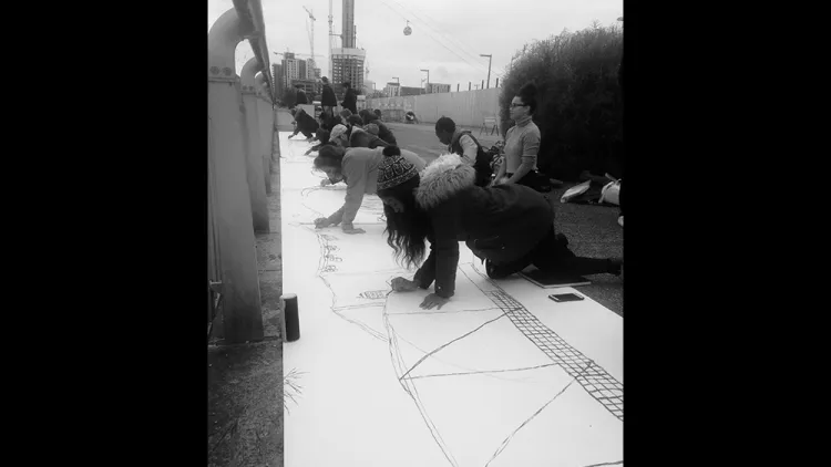 Students working on a drawing on the floor by the river thames