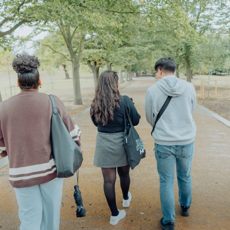 Four students walking along a path in Greenwich Park and chatting