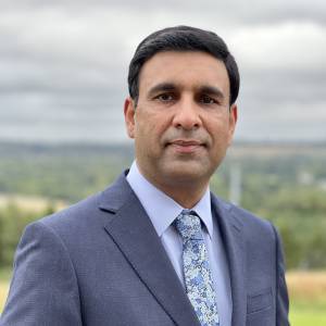 Ajaz Ali headshot man wearing a grey suit