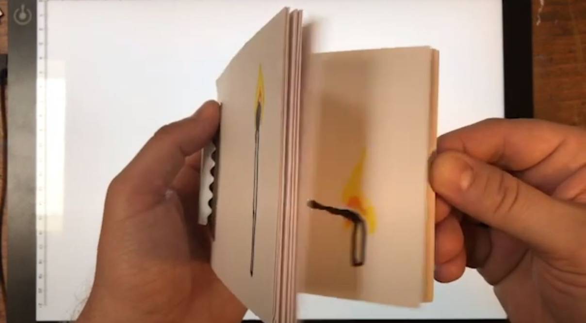 a pair of hands flipping through the finished flipbook, showing the match burning animation