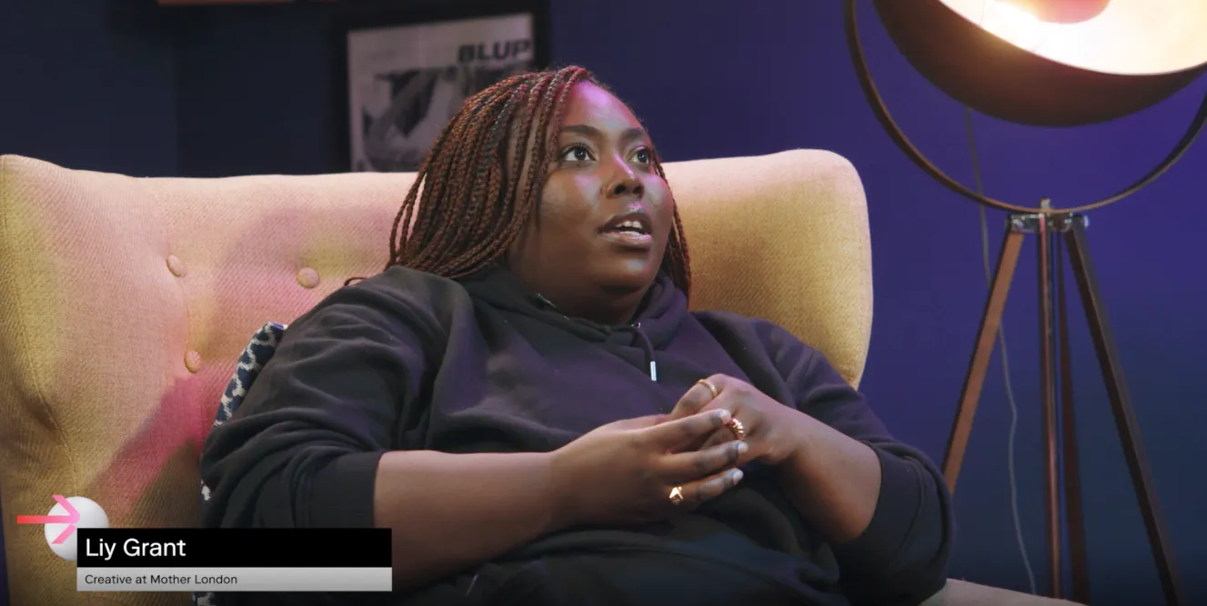Black woman with long brown braids sits in a mustard yellow armchair wearing a black hoodie