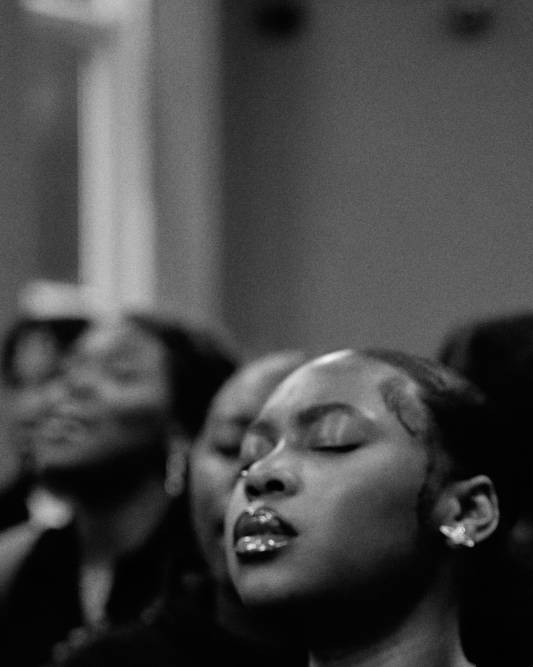Black and white photograph shows women with her eyes closed at church service