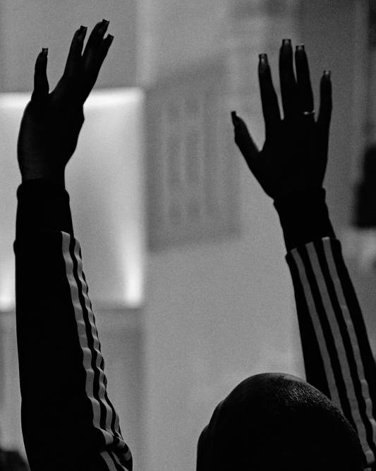 Black and white image of a person with their hands in the air in worship