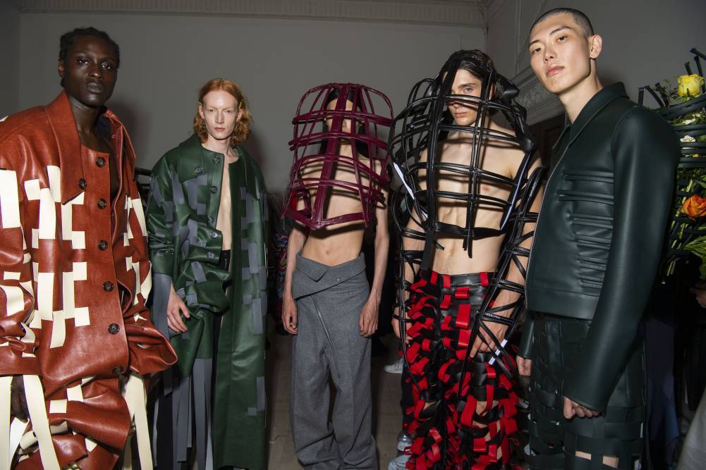 male models wear Avant Garde outfits with tags and cages 