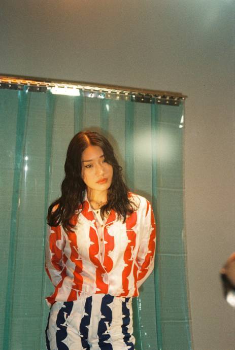 DJ Peggy Gou stands before a transparent curtain