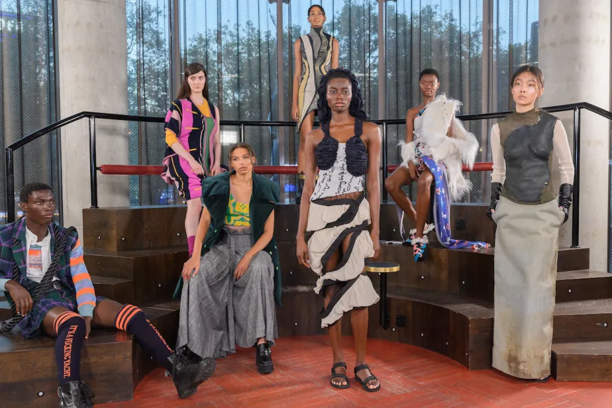 Models pose in front of wooden steps and large glass window