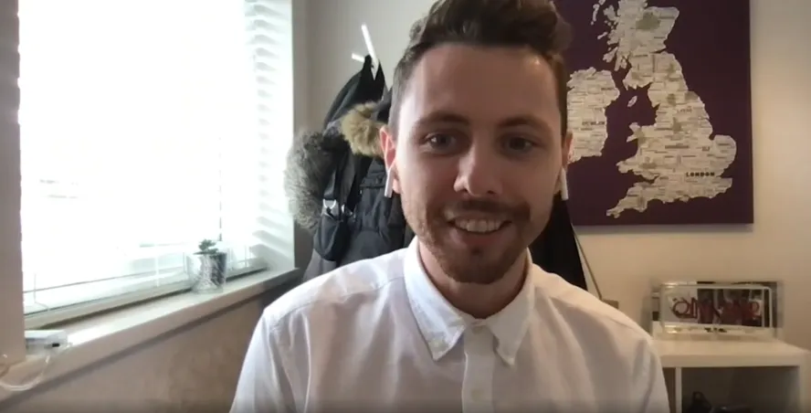 Man in white shirt and brown hair smiles at the camera