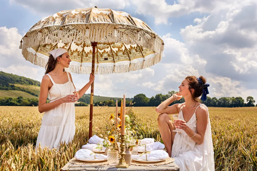 Two women enjoy a picnic in a wheat field