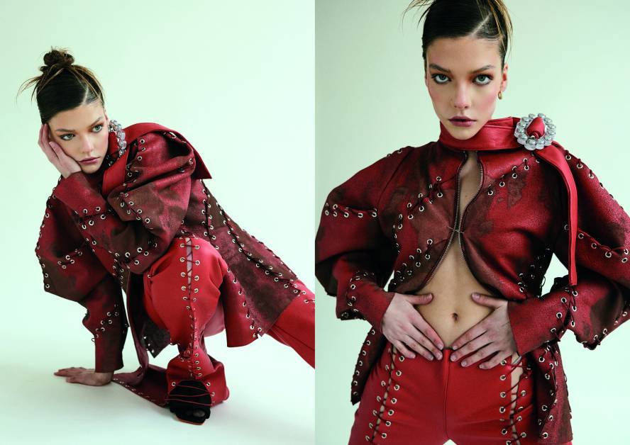 Model in red outfit poses against green background