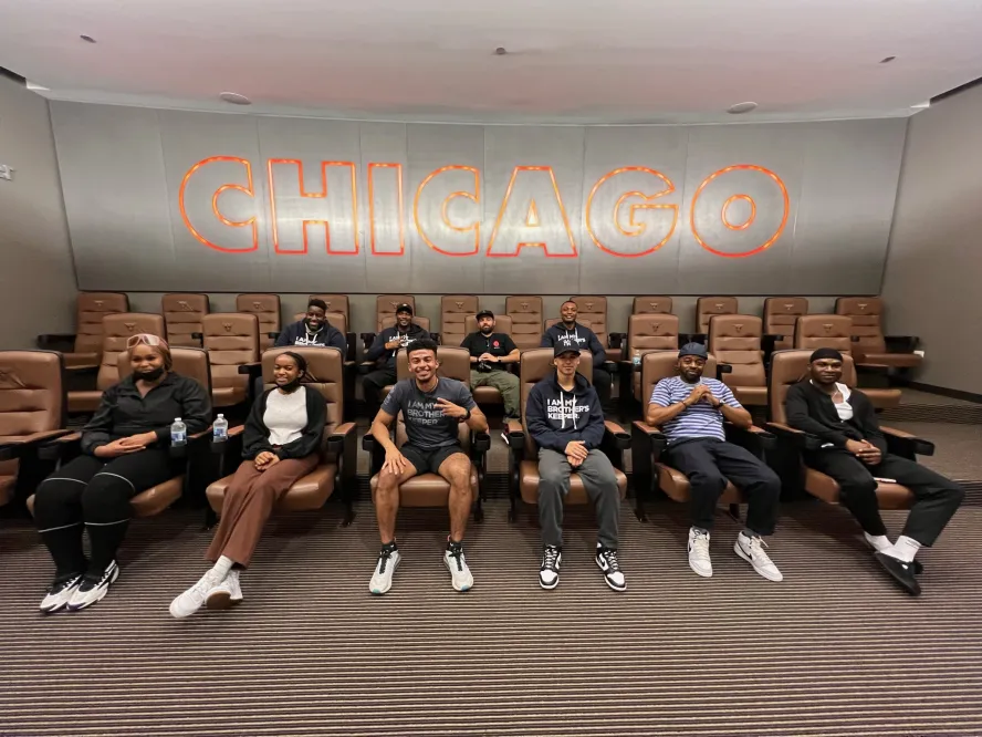 Row of students sit on seats below a large Chicago sign
