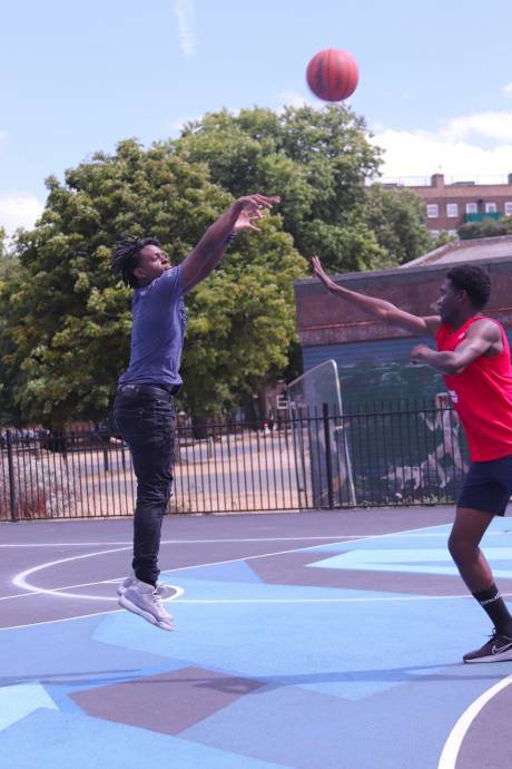 Two men playing basketball with the ball in the air 