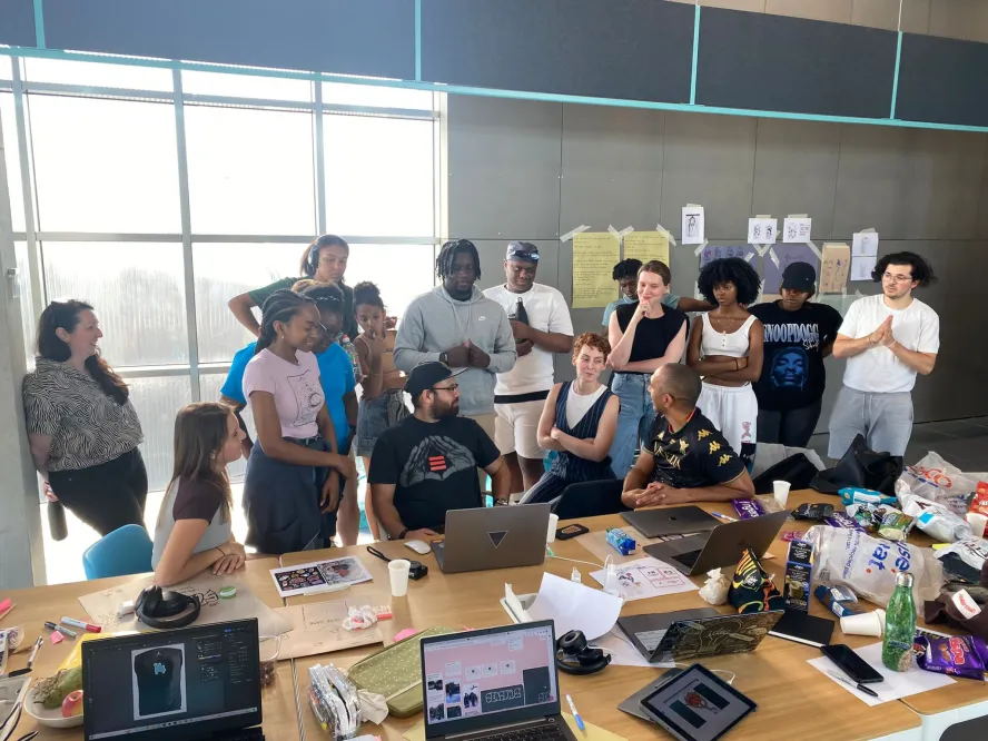 Group of students gather around a laptop