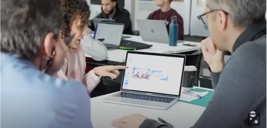 Students and staff from ITV looking at a laptop screen.