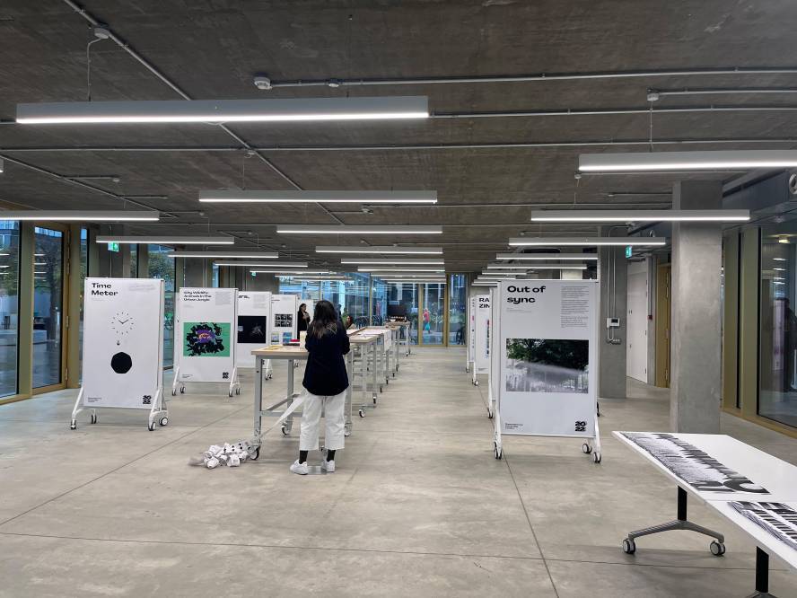 inside the design communication degree show. Students work is neatly lined up on display boards.