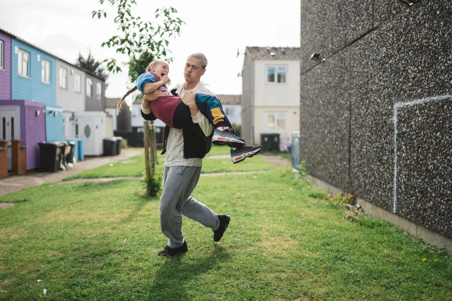 A young man carries a girl up by his chest