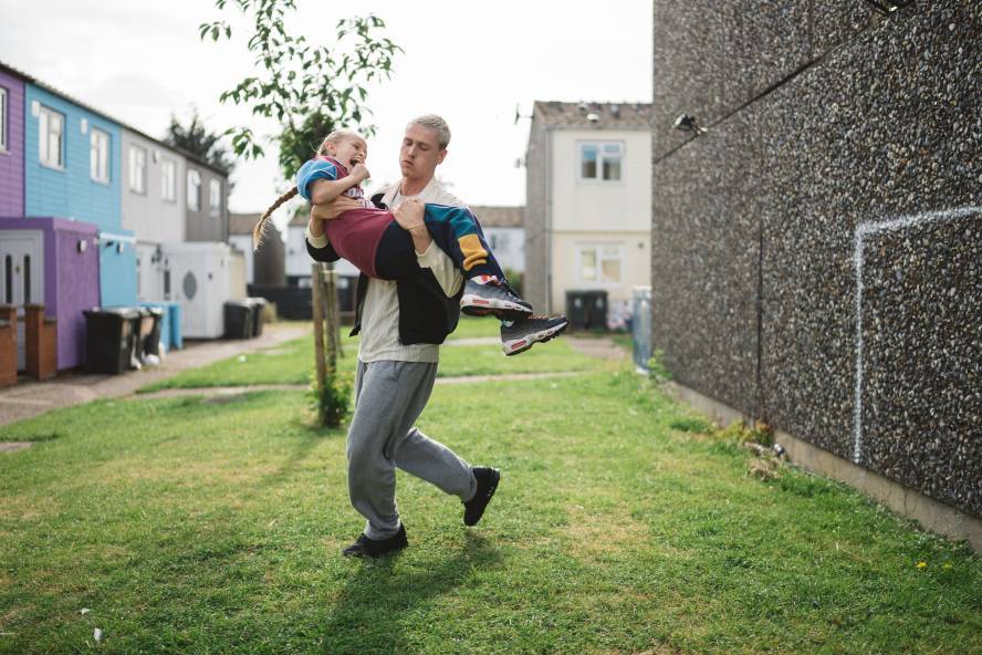 A young man carries a girl up by his chest