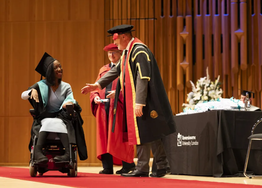 Graduate collects scroll on stage at graduation