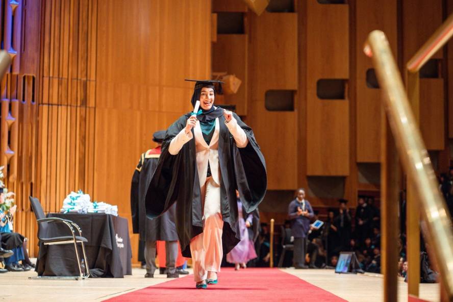 Graduate looks jubilant as they receive their scroll on stage