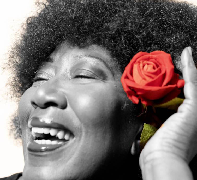 Black and white profile photo of smiling woman with a rose in her hair