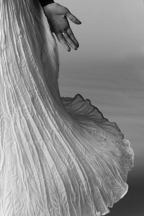 Black and white photo of a hand next to white dress by Ravensbourne MA photography student