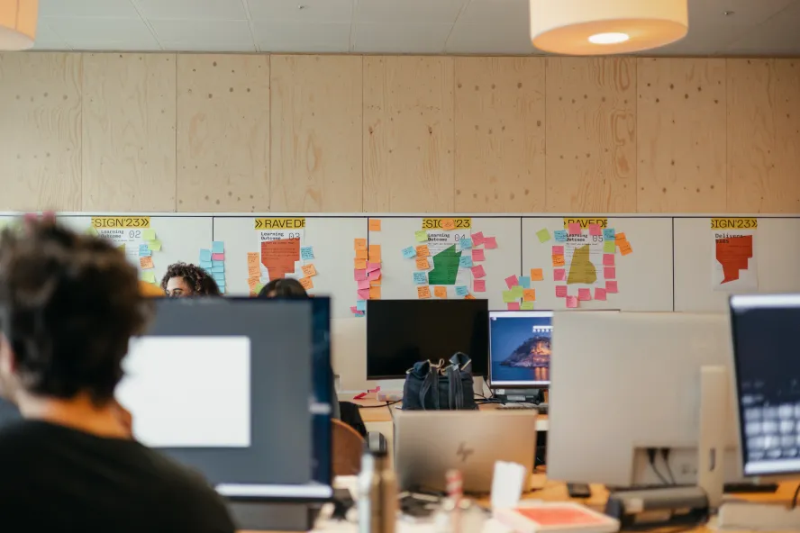 Students working in R3 study space at Ravensbourne University with a whiteboard with post it notes in background