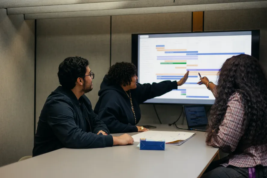 Business students in classroom pointing at presentation