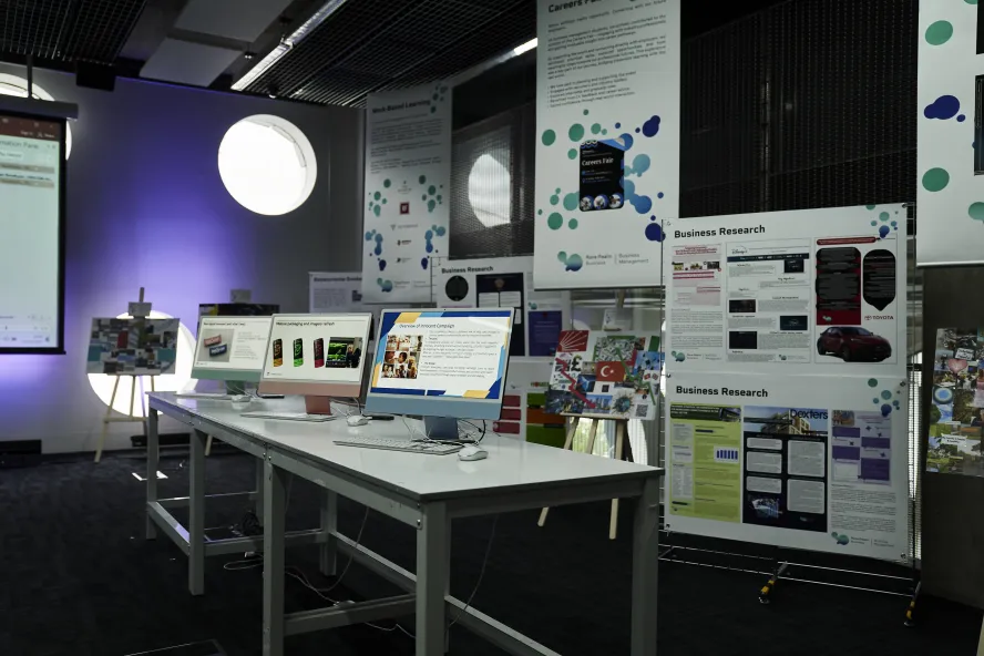 Ravensbourne Business Management students' work being displayed on posters and monitors at a Degree Show